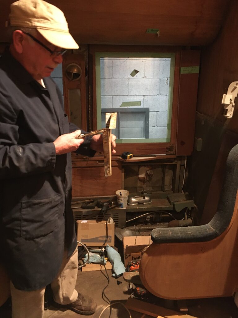 Volunteer Len, part of the restoration team, holding a tool inside the Cape Race compartment he is working in.