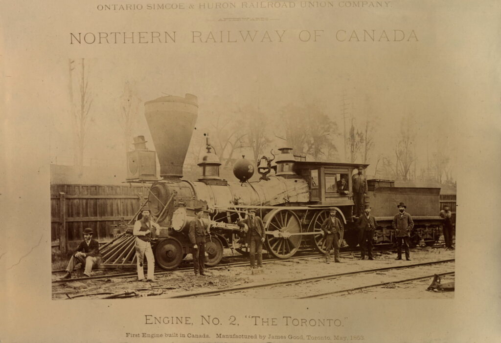 Photograph showing workers posing on an early steam locomotive
