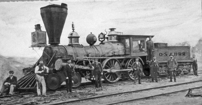 Ten workers pose on and around a locomotive.