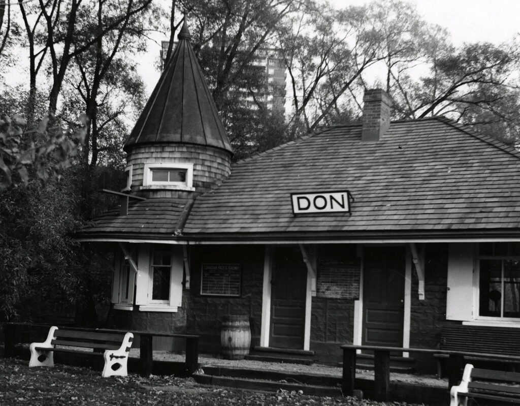 Historical photo of Don Station at Todmorden Mills Heritage site. The station doors are shut and there are benches to sit on in front of the station.