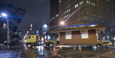 Nighttime photo of Don Station being hauled by track and trailer. The edge of the crystal at the Royal Ontario Museum can be seen in the frame.