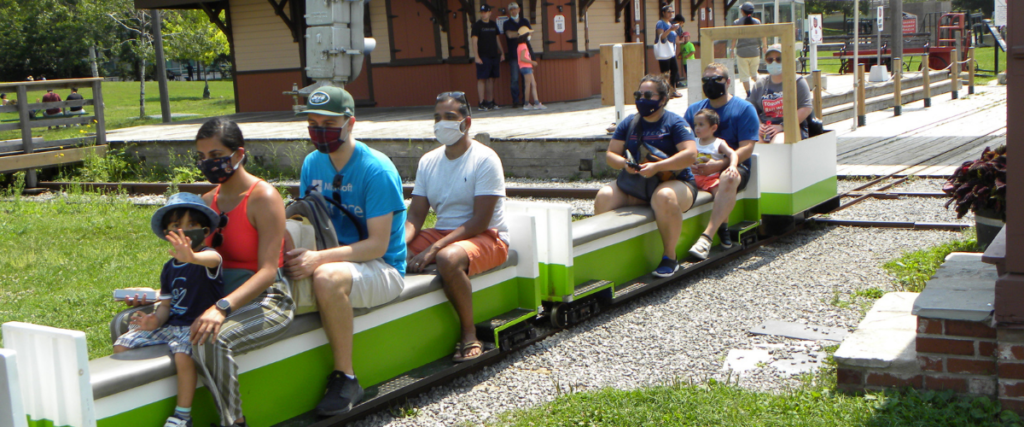 The Mini Train departs Don Station with groups of masked riders aboard.
