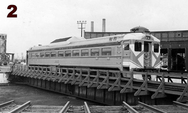 A single-level passenger train car on a turntable bridge with wooden railings.