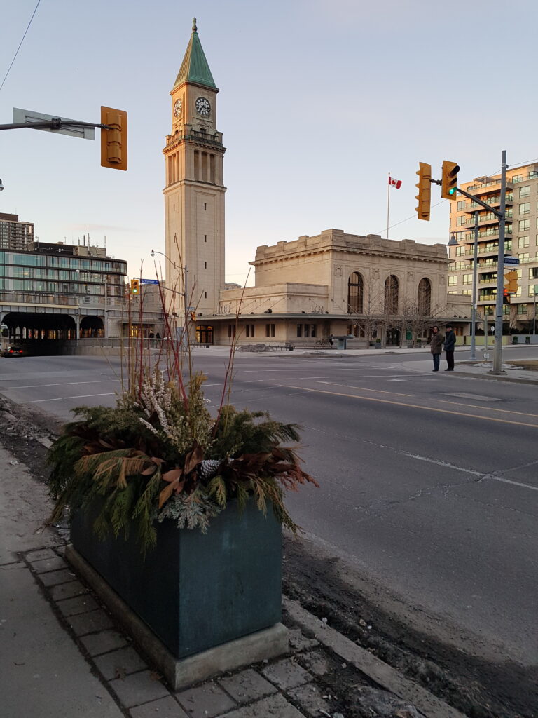 Street-level view of a beige stone building with a clock tower