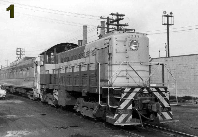 Black and white photo of a diesel locomotive hauling a passenger car in the John Street Roundhouse yard.