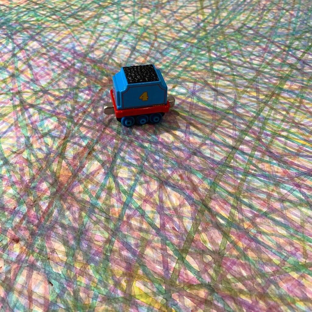 Detail of a painting made with a child's train toy with many layered colour lines made by train wheels