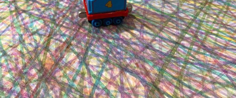 Detail of a painting made with a child's train toy with many layered colour lines made by train wheels