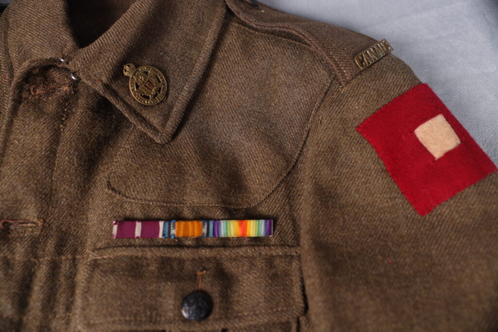 Close up of a multi-colour military ribbon bar and red shoulder patch on a uniform jacket
