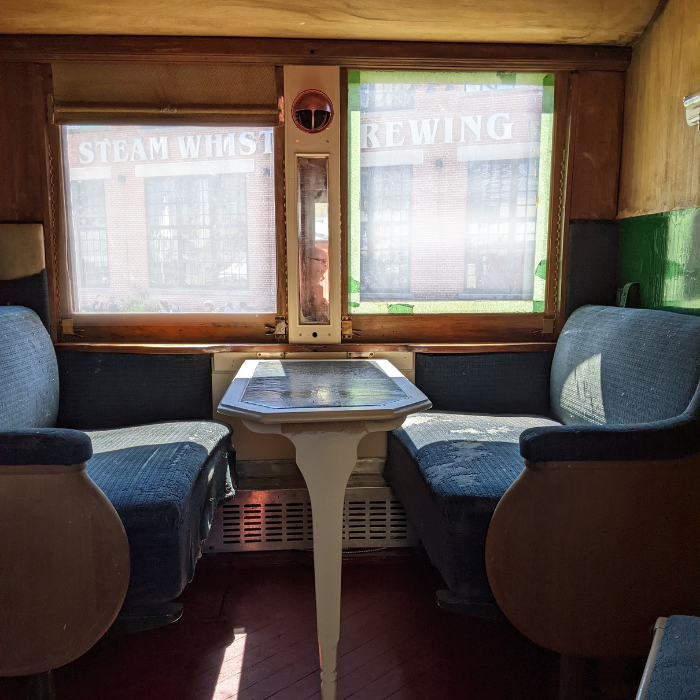 Inside a passenger train compartment with foldable table and blue berths